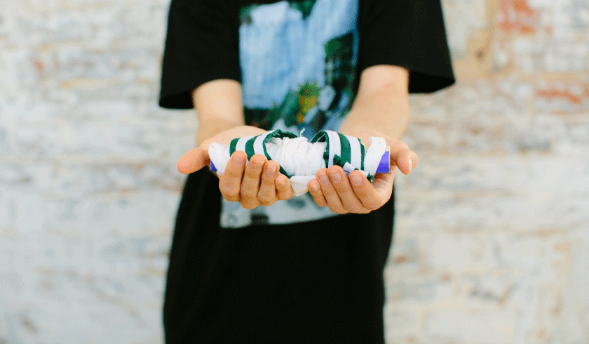 Image shows two hands holding a piece of wrap art. 